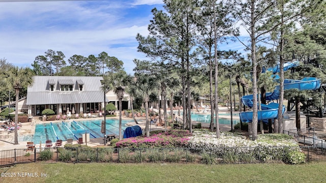 community pool featuring a water slide and fence