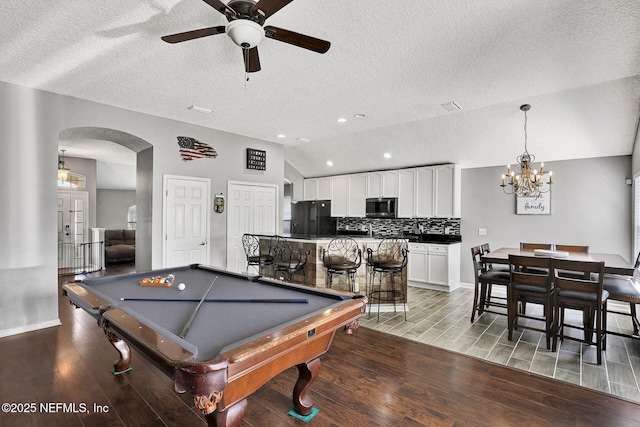 playroom featuring billiards, arched walkways, lofted ceiling, light wood-type flooring, and ceiling fan with notable chandelier