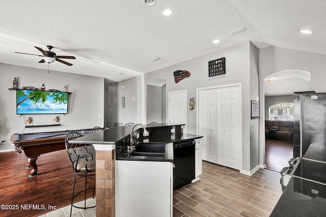 kitchen with a sink, arched walkways, dishwasher, and a ceiling fan
