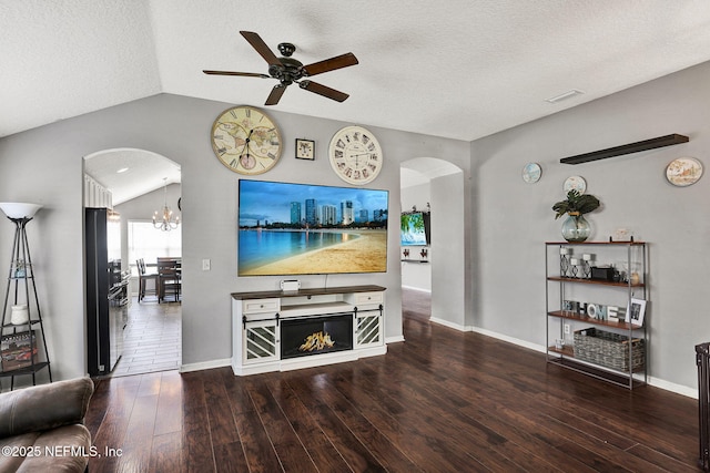 living room featuring wood-type flooring, a ceiling fan, arched walkways, and vaulted ceiling