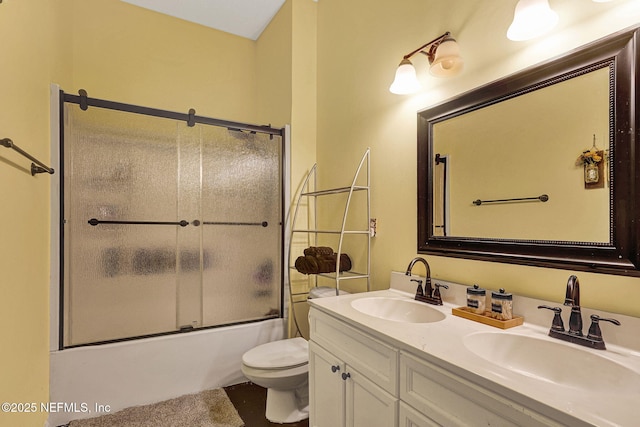 bathroom with double vanity, a sink, toilet, and enclosed tub / shower combo