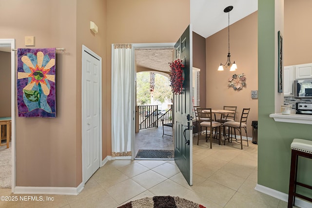 entryway featuring an inviting chandelier, light tile patterned floors, and a towering ceiling