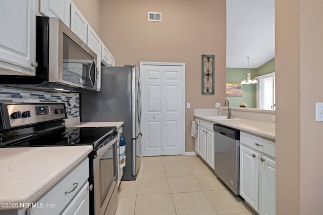 kitchen featuring stainless steel appliances, backsplash, a sink, visible vents, and white cabinets