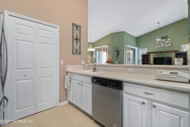kitchen with dishwasher, a sink, light tile patterned flooring, and vaulted ceiling