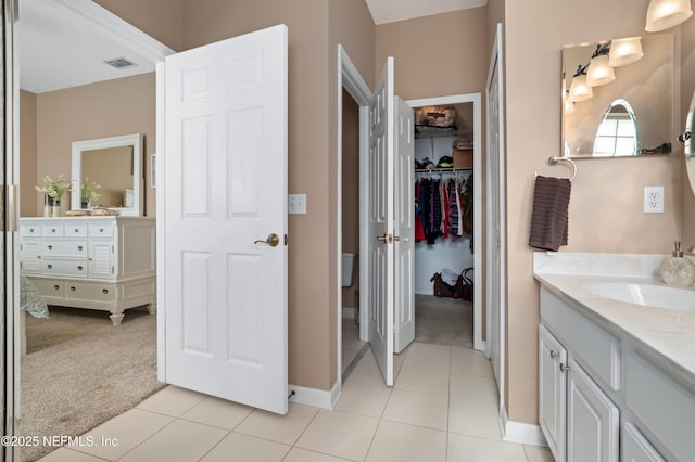 bathroom featuring visible vents, tile patterned floors, a walk in closet, and vanity