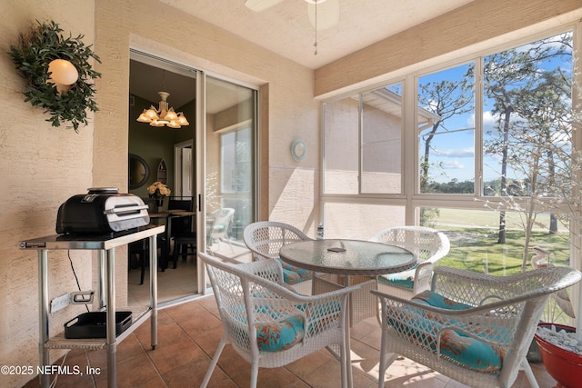 sunroom / solarium with tile patterned floors, a notable chandelier, and a textured wall