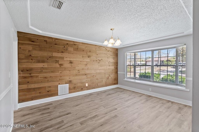 1967 Sussex Dr S, Orange Park, FL 32073 - unfurnished room with wood walls, a textured ceiling, visible vents, a notable chandelier, and wood finished floors