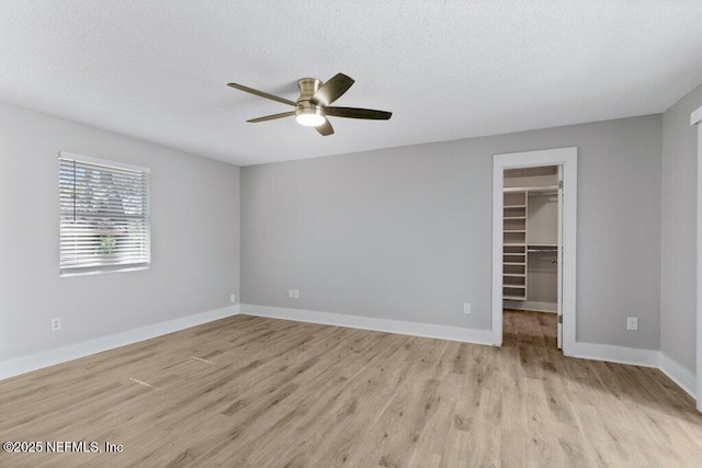 1967 Sussex Dr S, Orange Park, FL 32073 - unfurnished bedroom featuring a walk in closet, baseboards, light wood-style floors, and a textured ceiling