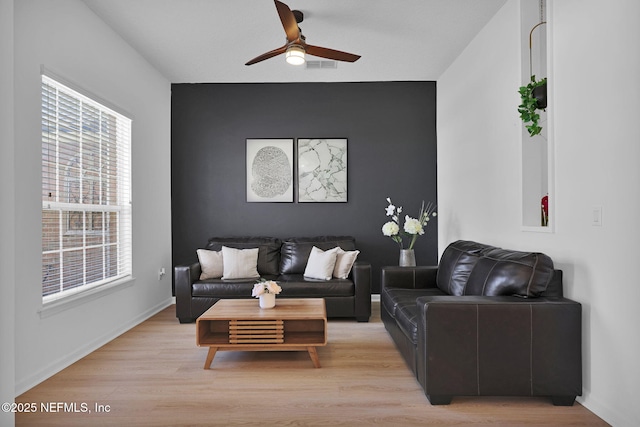 living area featuring baseboards, ceiling fan, visible vents, and light wood-type flooring