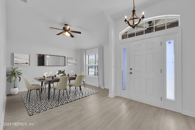 entryway featuring ceiling fan with notable chandelier, baseboards, lofted ceiling, and wood finished floors