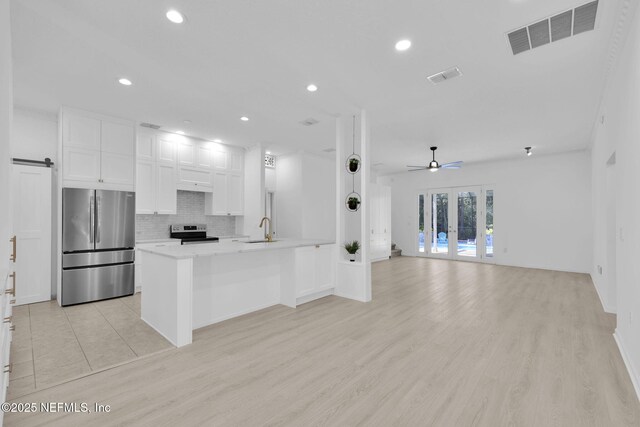 kitchen featuring white cabinetry, stainless steel appliances, backsplash, a sink, and visible vents