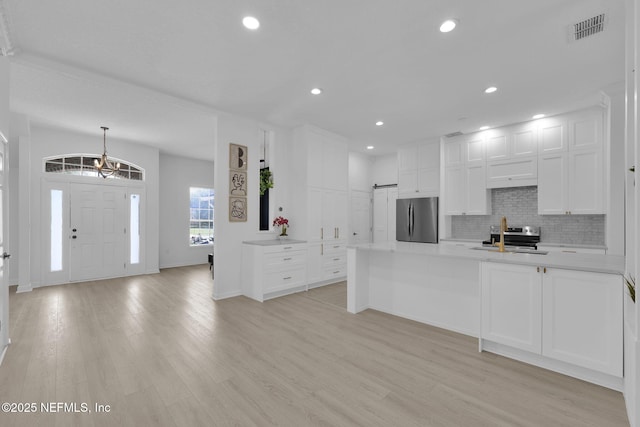 kitchen with light countertops, backsplash, a sink, visible vents, and freestanding refrigerator