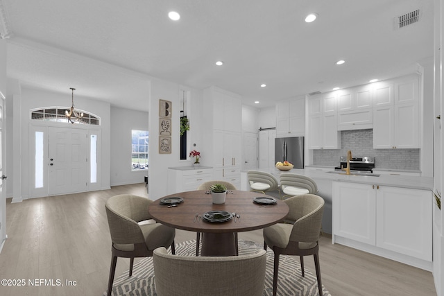 dining area with light wood-style flooring, visible vents, baseboards, recessed lighting, and a barn door