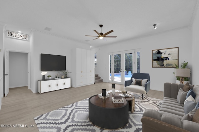 living room featuring baseboards, light wood-type flooring, ceiling fan, and french doors