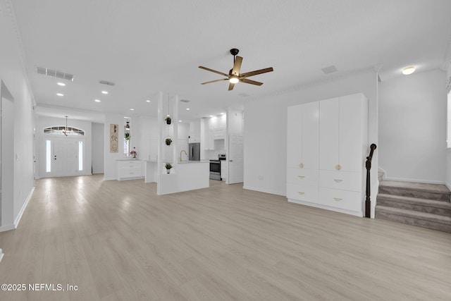 unfurnished living room with stairs, visible vents, and light wood finished floors