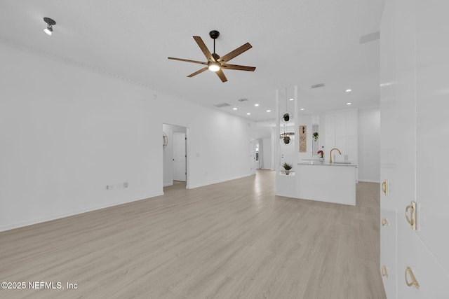 unfurnished living room with recessed lighting, baseboards, a sink, light wood finished floors, and a ceiling fan