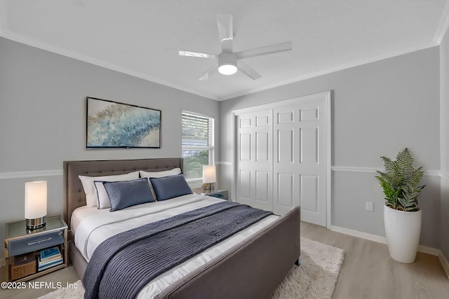 bedroom with crown molding, light wood-type flooring, baseboards, a ceiling fan, and a closet