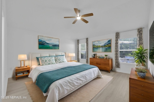 bedroom featuring multiple windows, a ceiling fan, and light wood finished floors