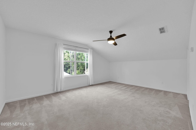 bonus room featuring vaulted ceiling, carpet flooring, a ceiling fan, a textured ceiling, and visible vents