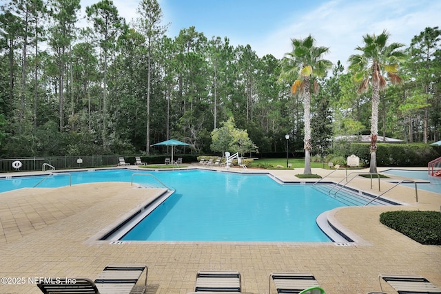 community pool with fence and a patio area