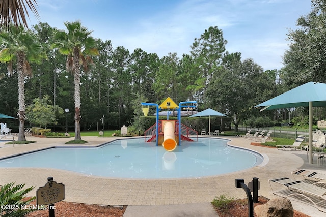 view of swimming pool with fence, playground community, and a water play area