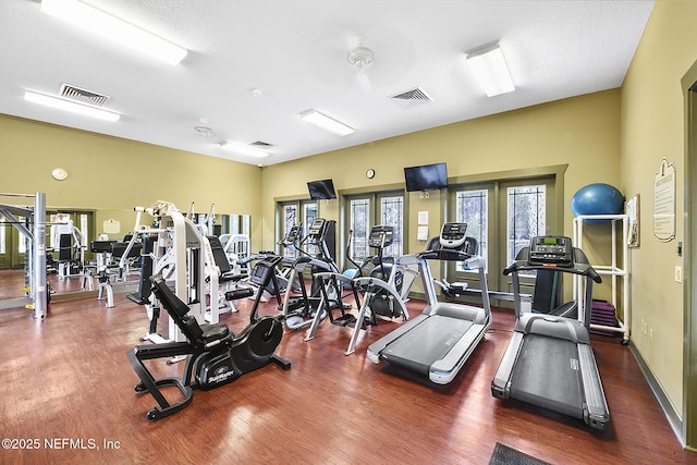 workout area featuring a textured ceiling, visible vents, and wood finished floors