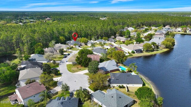 drone / aerial view with a water view, a wooded view, and a residential view