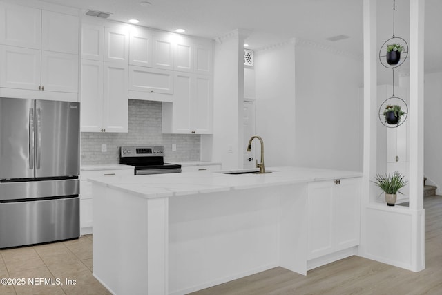 kitchen featuring light stone counters, a sink, white cabinetry, stainless steel appliances, and decorative backsplash