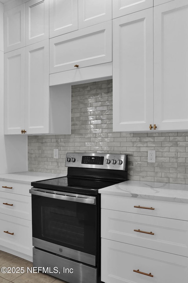 kitchen featuring white cabinets, decorative backsplash, stainless steel electric range, and light stone counters