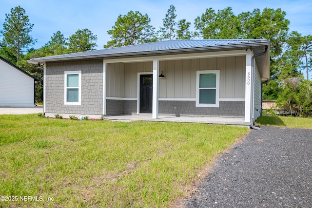 view of front of home featuring a front lawn, metal roof, and a porch