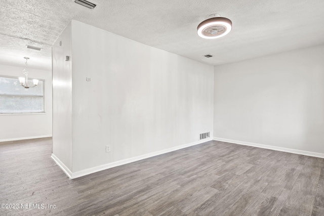3838 Winton Dr, Jacksonville, FL 32208 - unfurnished room with a notable chandelier, a textured ceiling, baseboards, and wood finished floors
