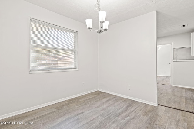 3838 Winton Dr, Jacksonville, FL 32208 - unfurnished room featuring a notable chandelier, wood finished floors, a textured ceiling, baseboards, and visible vents