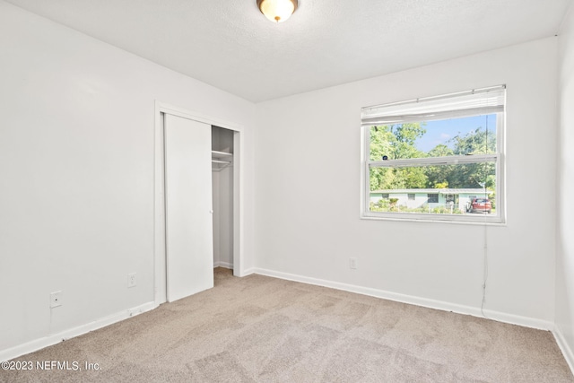 3838 Winton Dr, Jacksonville, FL 32208 - unfurnished bedroom featuring carpet flooring, baseboards, a closet, and a textured ceiling