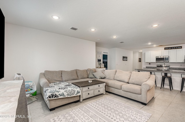 living area featuring light tile patterned floors, visible vents, and recessed lighting