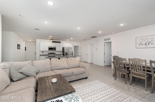 living area with light tile patterned flooring, visible vents, and recessed lighting