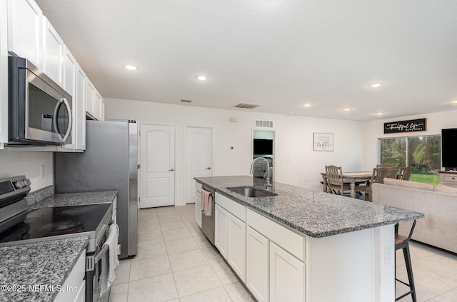 kitchen featuring light tile patterned floors, visible vents, a sink, a kitchen island with sink, and appliances with stainless steel finishes