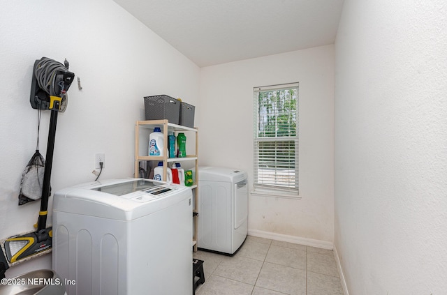 laundry area featuring light tile patterned floors, baseboards, washing machine and dryer, and laundry area