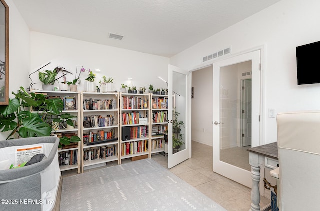 interior space with tile patterned flooring, french doors, and visible vents