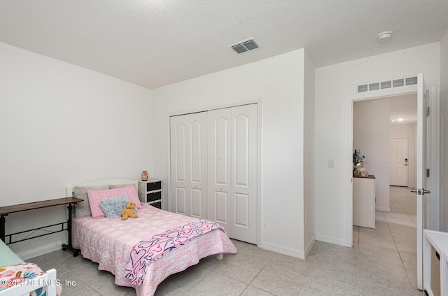 bedroom with a closet, light tile patterned floors, and visible vents