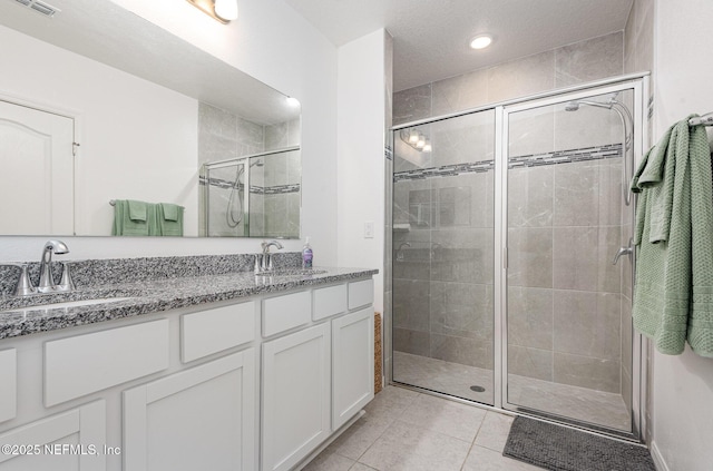 full bathroom featuring a shower stall, tile patterned flooring, double vanity, and a sink