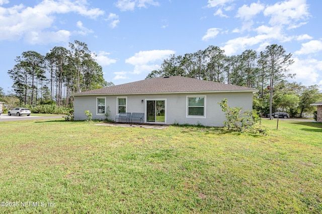 back of property with a yard and stucco siding