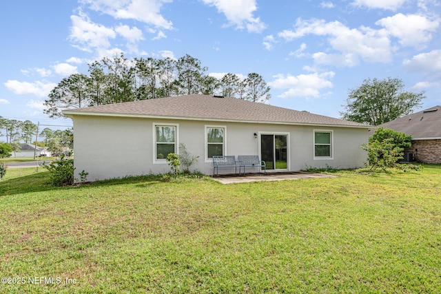 rear view of property with a shingled roof, a patio, stucco siding, and a lawn