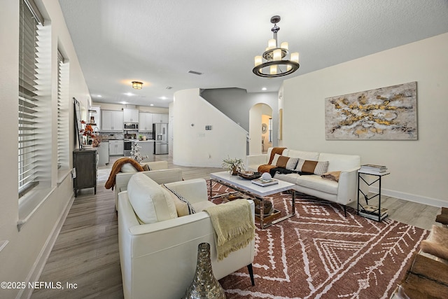 110 Arabian Ct, Saint Augustine, FL 32095 - living area with a textured ceiling, baseboards, arched walkways, light wood-style floors, and a notable chandelier