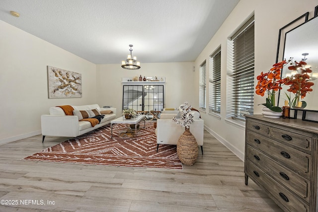 110 Arabian Ct, Saint Augustine, FL 32095 - living room featuring baseboards, a notable chandelier, light wood-style floors, and a textured ceiling