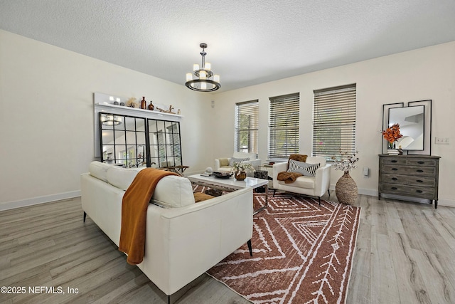 110 Arabian Ct, Saint Augustine, FL 32095 - living room featuring baseboards, a textured ceiling, an inviting chandelier, and light wood finished floors