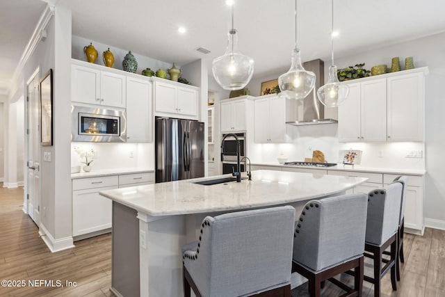 64 Whirlaway Ct, Saint Johns, FL 32259 - kitchen featuring stainless steel appliances, wall chimney range hood, a sink, a center island with sink, and light wood-style flooring