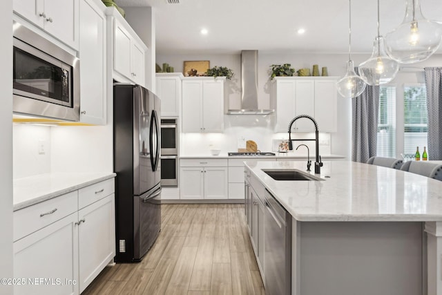64 Whirlaway Ct, Saint Johns, FL 32259 - kitchen featuring wall chimney exhaust hood, appliances with stainless steel finishes, a sink, a kitchen island with sink, and white cabinets