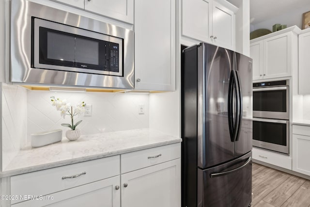 64 Whirlaway Ct, Saint Johns, FL 32259 - kitchen with appliances with stainless steel finishes, white cabinetry, decorative backsplash, light wood-type flooring, and light stone counters