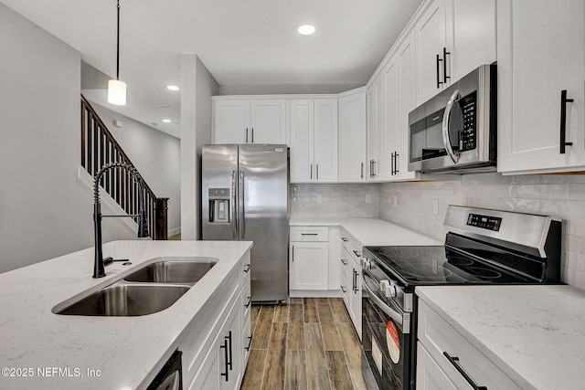 335 5th Ave S, Jacksonville Beach, FL 32250 - kitchen featuring a sink, light wood finished floors, light stone countertops, stainless steel appliances, and white cabinets