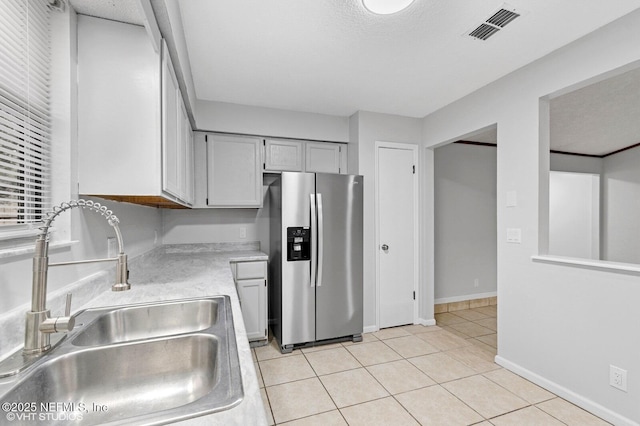 7927 Dwyer Dr, Jacksonville, FL 32244 - kitchen with light countertops, a sink, light tile patterned floors, visible vents, and stainless steel refrigerator with ice dispenser